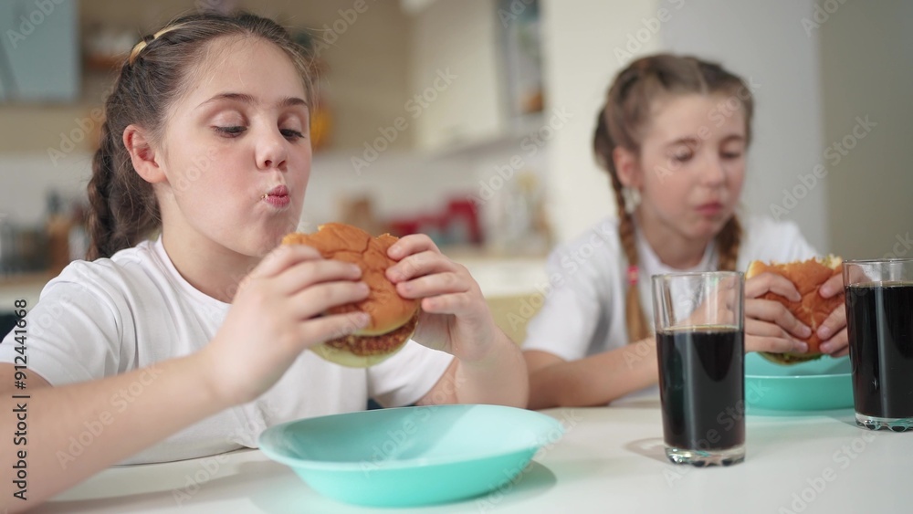 children group eating fast food in the kitchen. delicious breakfast unhealthy food lifestyle concept. children girls eat hamburgers and drink cola in the kitchen indoors. fast food concept children group eating fast food in the kitchen. delicious breakfast unhealthy food lifestyle concept. children girls eat hamburgers and drink cola in the kitchen indoors. fast food concept