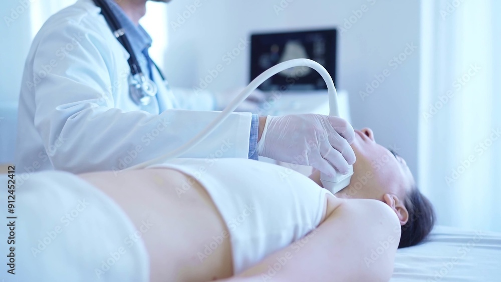 Naklejka premium Doctor man with white medical gloves is using ultrasound machine to examine neck of female patient lying down in clinic. Medicine concept
