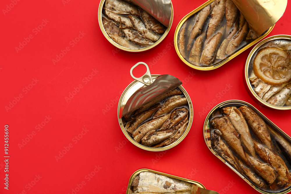 Opened tin cans with different fish on red background Opened tin cans with different fish on red background