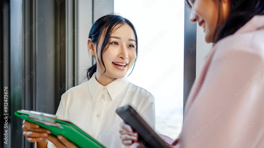 Obraz premium Young asian business woman hold the paper clipboard and digital tablet to show or consult or discussion to the colleague in the office in evening, Talk about investments, finances, profits and losses