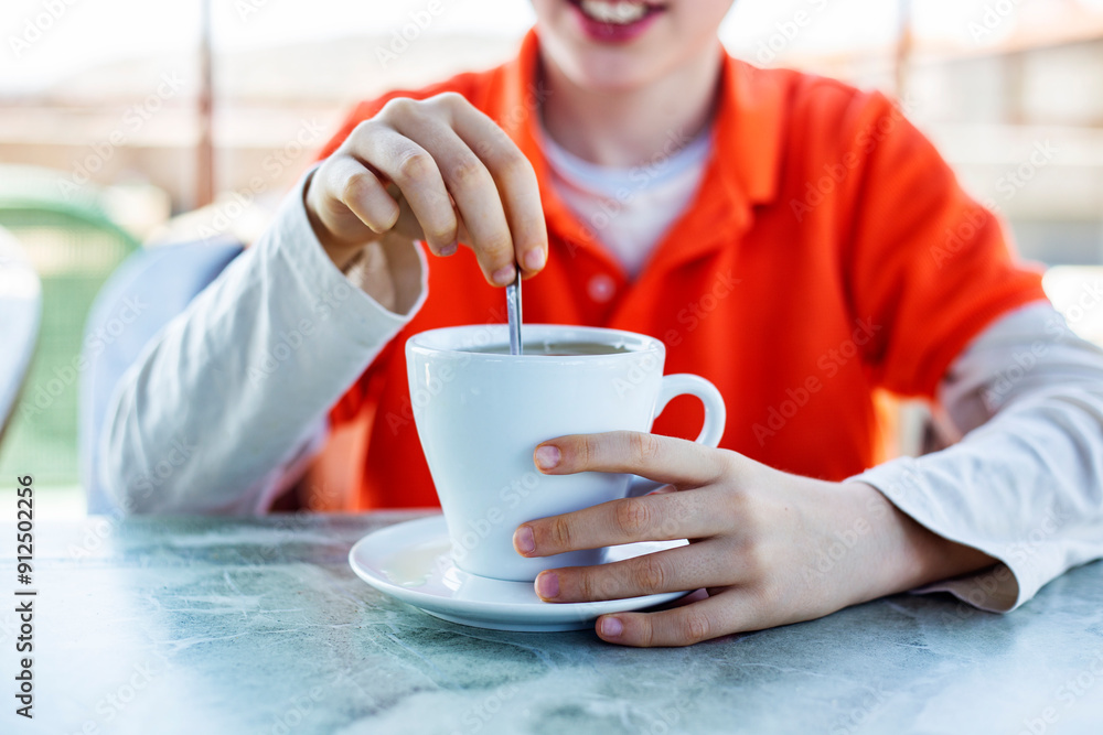 Close-up of boy holding spoon and cup of coffee in cafe Close-up of boy holding spoon and cup of coffee in cafe