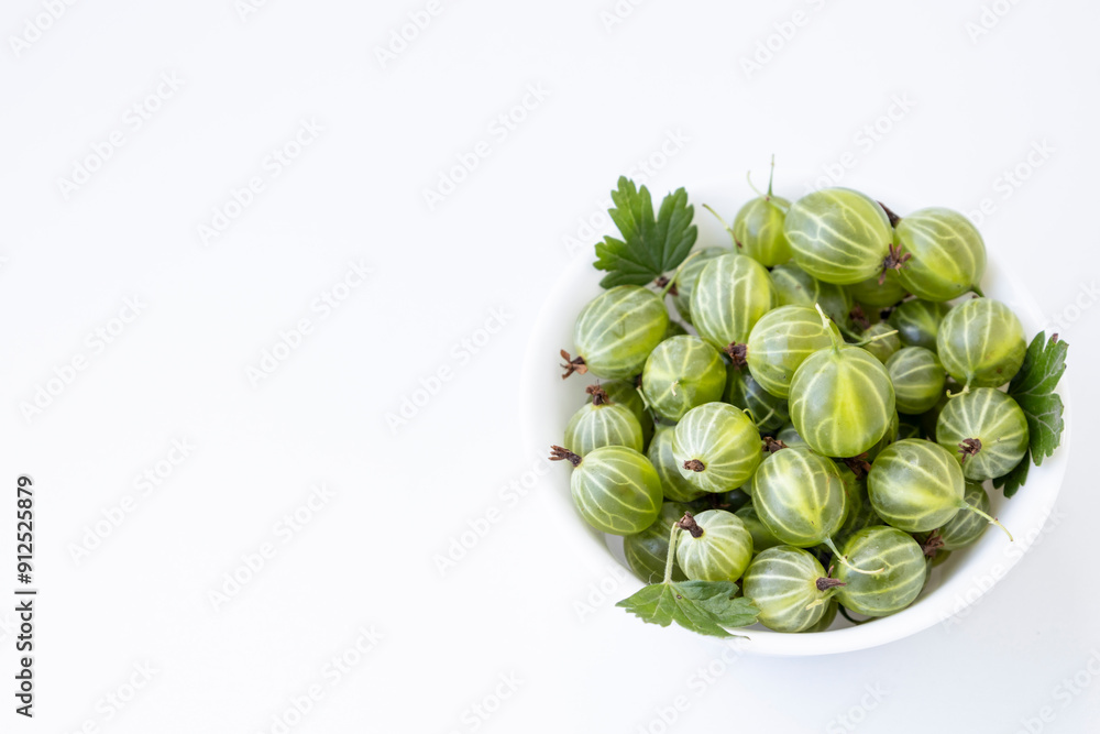 Gooseberry fruit with leaf springs on the white plate over white background. Succulent fresh ripe green organic berries Gooseberry Gooseberry fruit with leaf springs on the white plate over white background. Succulent fresh ripe green organic berries Gooseberry