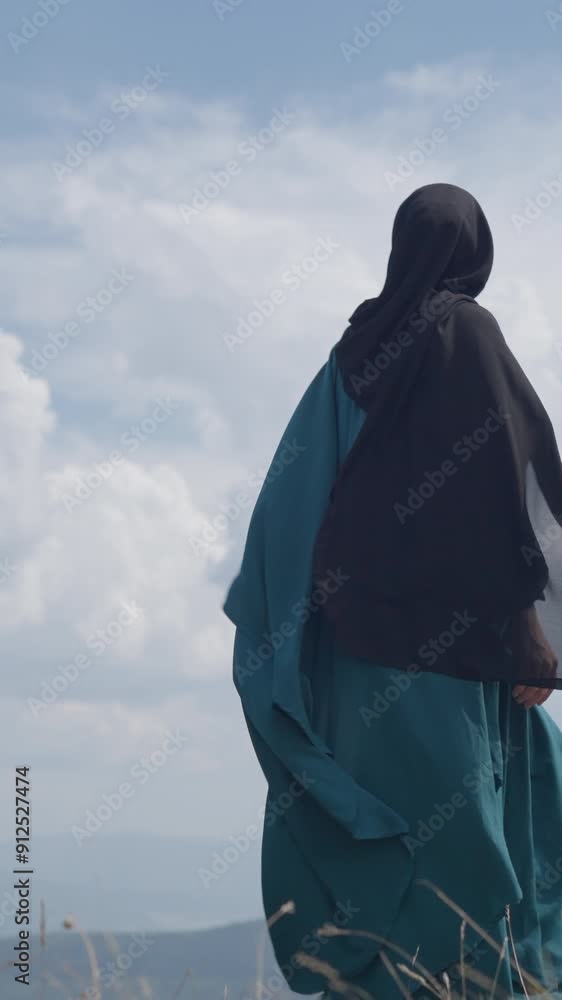 Vertical Screen: Rear View of a Stylish Muslim Woman Elegantly Walking on a Mountain as the Wind Flutters Her Dress and Scarf. Concept of Grace, Freedom, Fashion, Faith, Religion, Islam, Headscarf Vertical Screen: Rear View of a Stylish Muslim Woman Elegantly Walking on a Mountain as the Wind Flutters Her Dress and Scarf. Concept of Grace, Freedom, Fashion, Faith, Religion, Islam, Headscarf