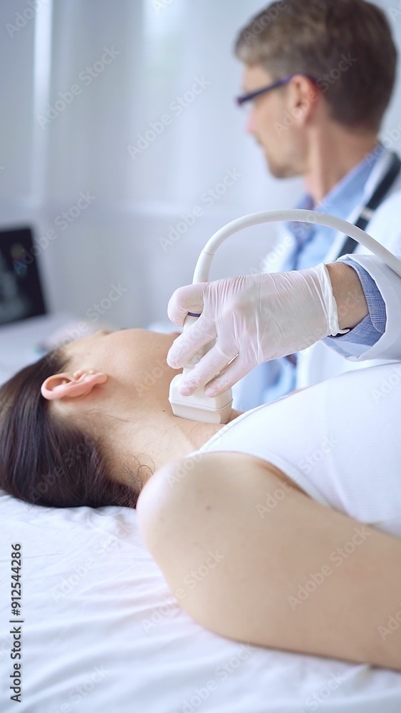 Obraz premium Doctor man wearing white protective gloves is using ultrasound equipment on the neck of patient woman, lying for examination. Medicine concept