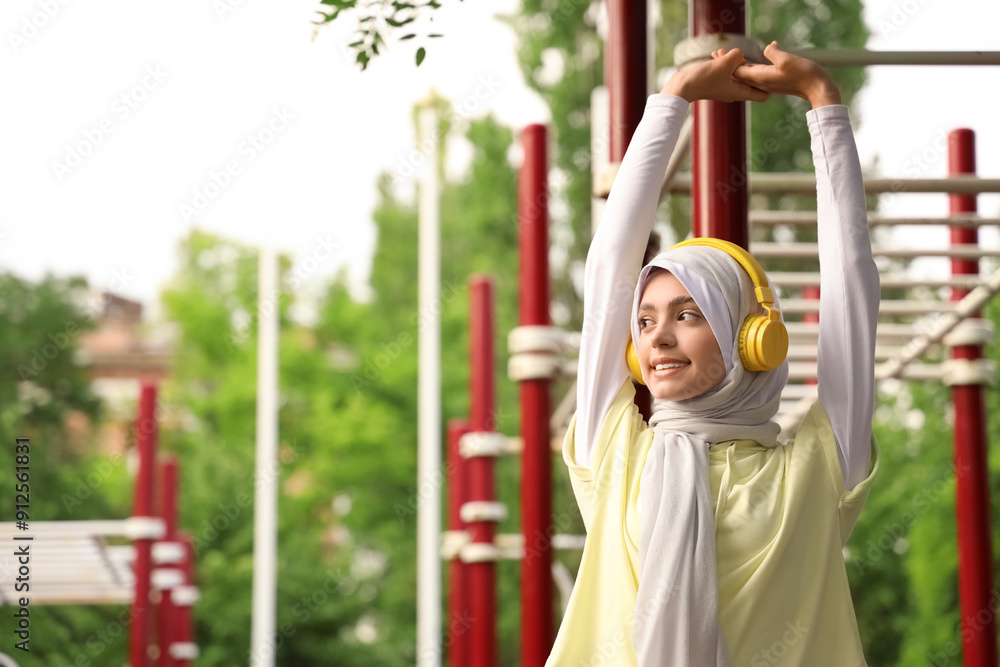 Fototapeta premium Sporty Muslim woman in headphones training outdoors
