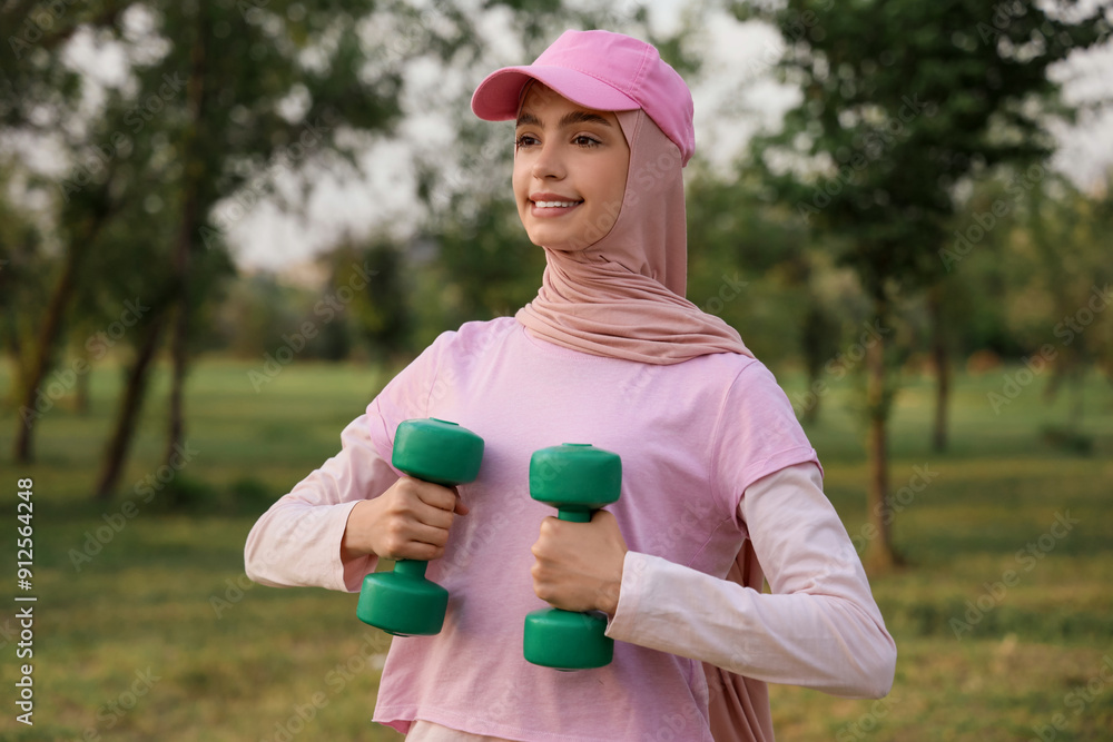 Sporty Muslim woman with dumbbells training in park Sporty Muslim woman with dumbbells training in park