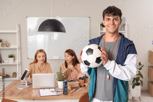 Male PE teacher with soccer ball in school office