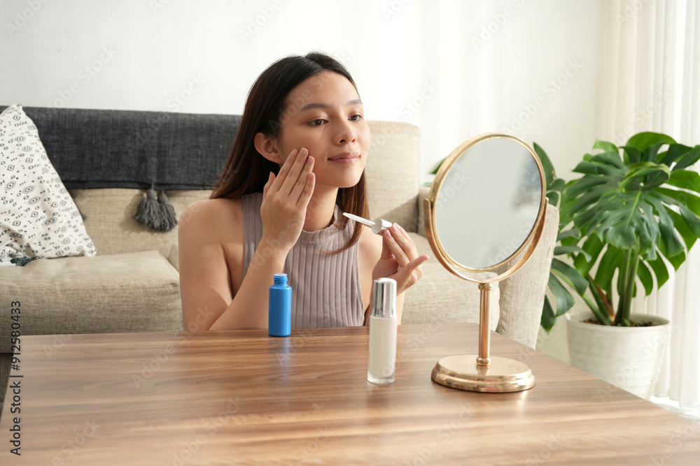 A woman touches her face gently while applying makeup, reflecting self-care and focus. The bright room offers a peaceful setting for her beauty routine. A woman touches her face gently while applying makeup, reflecting self-care and focus. The bright room offers a peaceful setting for her beauty routine.