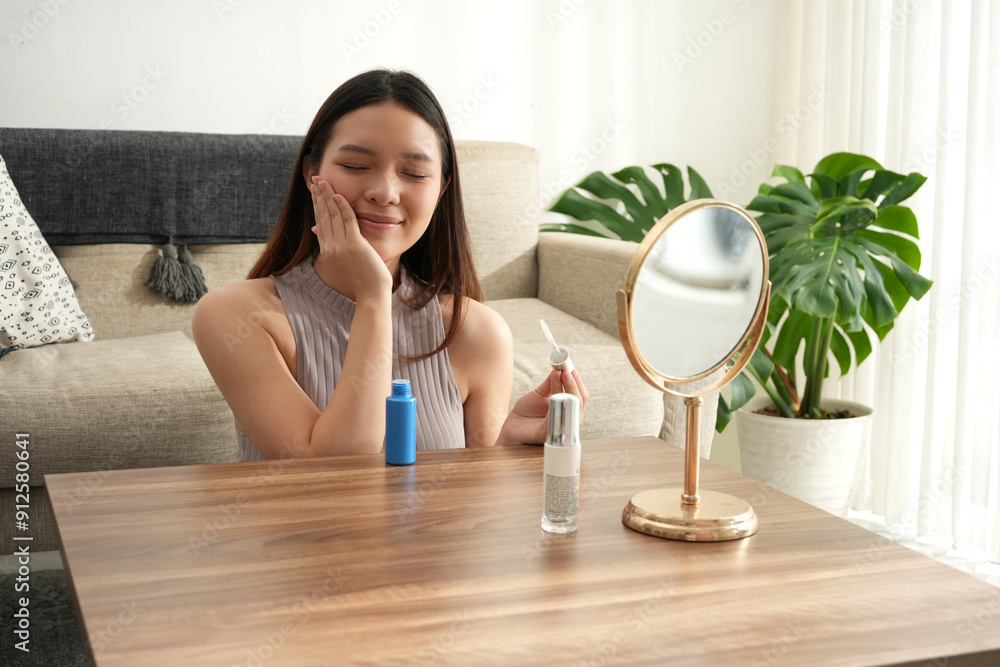 A woman touches her face gently while applying makeup, reflecting self-care and focus. The bright room offers a peaceful setting for her beauty routine. A woman touches her face gently while applying makeup, reflecting self-care and focus. The bright room offers a peaceful setting for her beauty routine.
