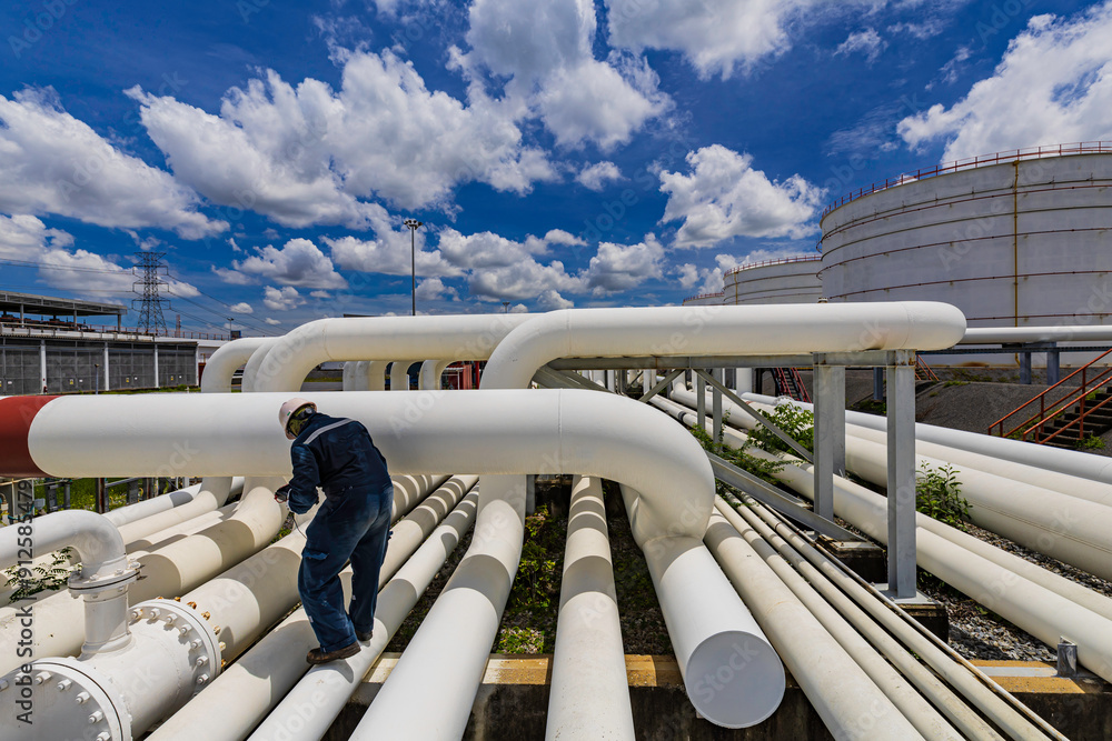 Male worker inspection at steel long pipes and pipe elbow in station oil factory during refinery valve of visual check Male worker inspection at steel long pipes and pipe elbow in station oil factory during refinery valve of visual check