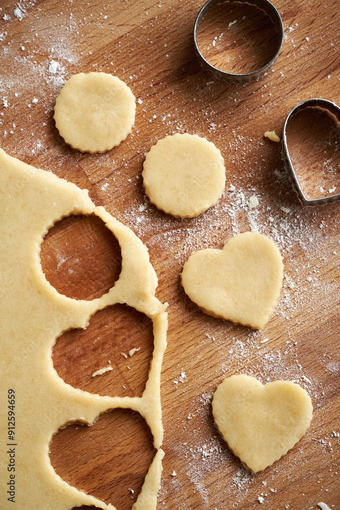 Cutting out heart and circle shapes from rolled out pastry dough to prepare traditional Linzer Christmas cookies Cutting out heart and circle shapes from rolled out pastry dough to prepare traditional Linzer Christmas cookies