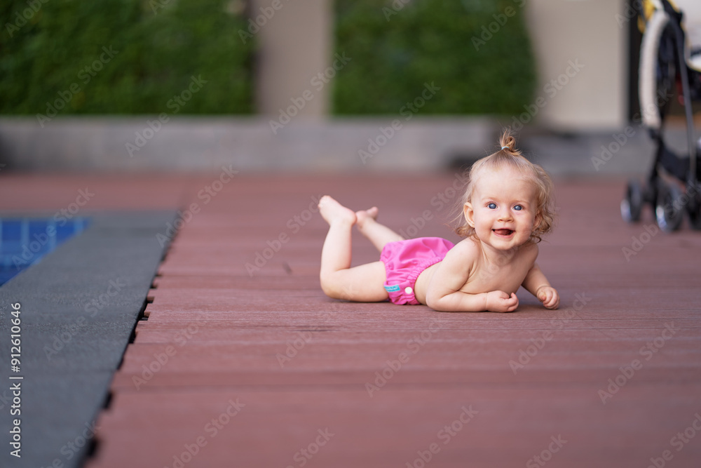 Naklejka premium Little baby girl near swimming pool outdoors.