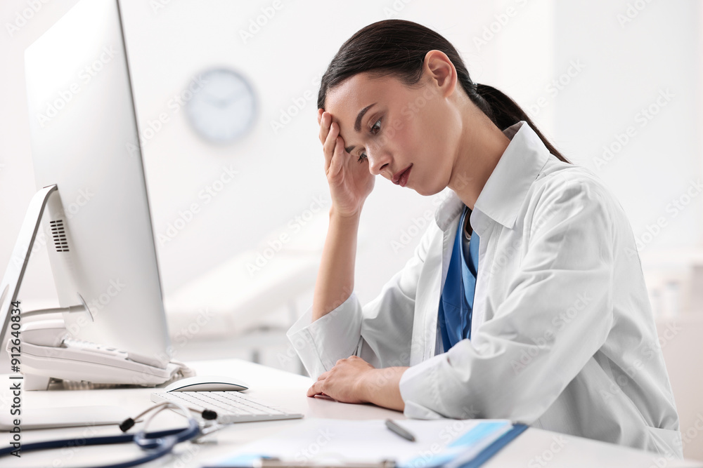 Tired nurse sitting at table in clinic Tired nurse sitting at table in clinic