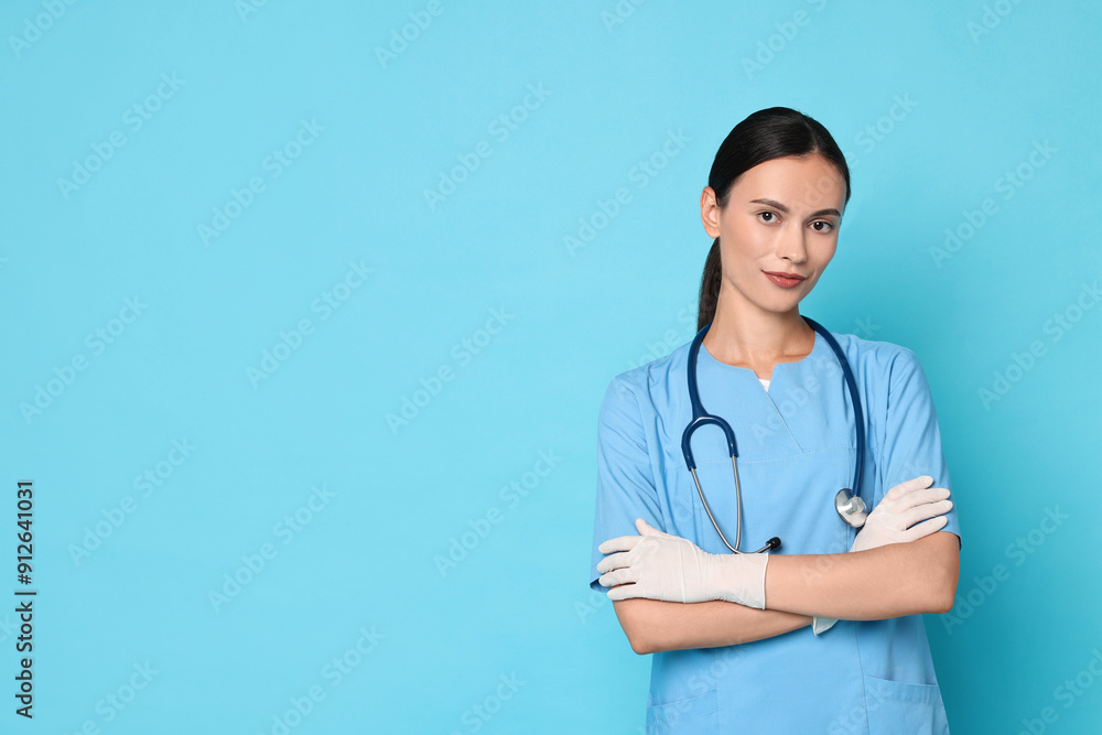 Beautiful nurse with crossed arms on light blue background. Space for text Beautiful nurse with crossed arms on light blue background. Space for text