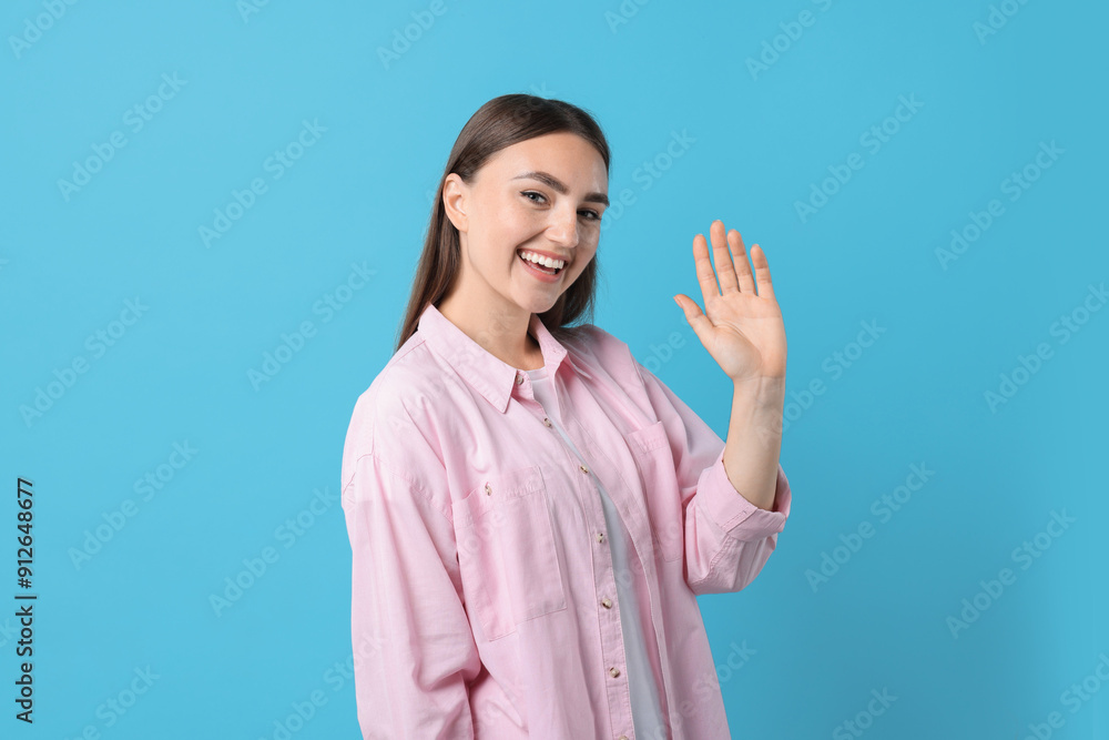 Happy woman waving on light blue background Happy woman waving on light blue background