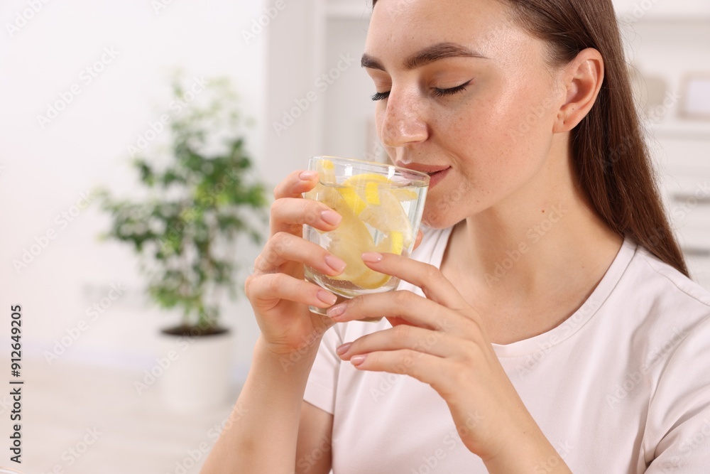 Woman drinking water with lemon indoors, closeup. Space for text Woman drinking water with lemon indoors, closeup. Space for text