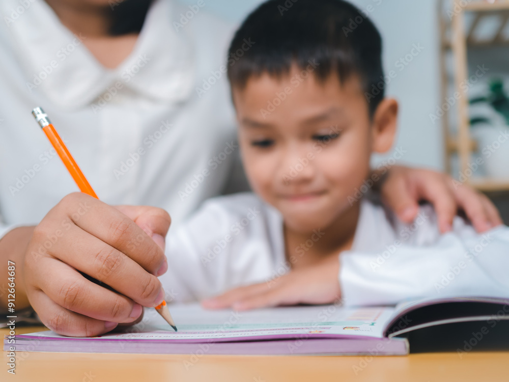 Teacher or mother helping boy writing lesson and learning to write, Education home school concept, Female tutor helping little elementary school boy with homework during individual lesson at home Teacher or mother helping boy writing lesson and learning to write, Education home school concept, Female tutor helping little elementary school boy with homework during individual lesson at home