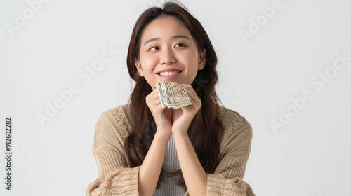 Cheerful Asian woman with South Korean won money in hands, looking thoughtful and smiling, isolated on white background