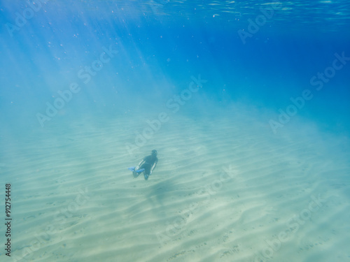 A person is swimming in the ocean with a surfboard