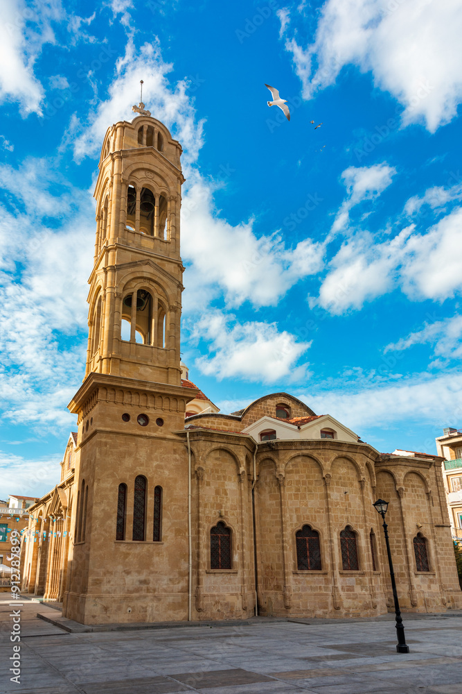 Fototapeta premium A small building with a blue door sits in front of a large Mosque with a tall tower in Nicosia, Cyprus. Beautiful street with old architecture in Nicosia, Cyprus.