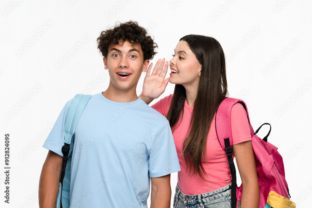Naklejka premium Pretty girl high school pupil student teenager whispering in the ear secret to boyfriend boy classmate, friends gossip together, hot news wear casual clothes backpack stands against white background