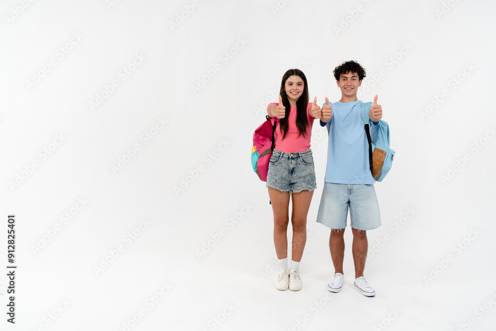 Full length size of high school pupils students teenagers classmates boy girl friends in casual with bags showing thumb up sign gesture isolated on white background copy space. Education concept Full length size of high school pupils students teenagers classmates boy girl friends in casual with bags showing thumb up sign gesture isolated on white background copy space. Education concept