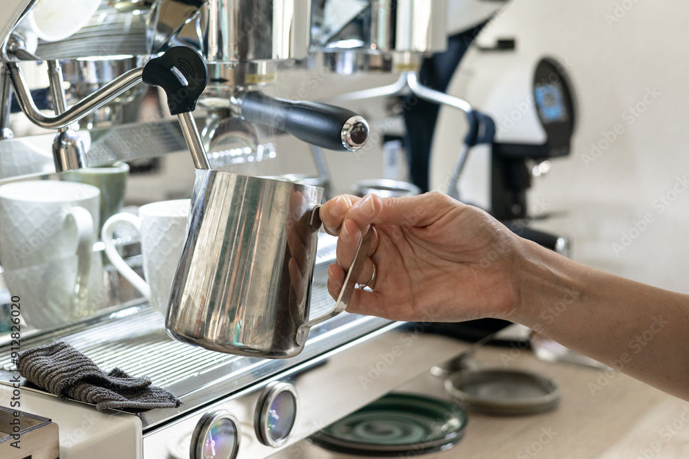 A barista whips milk for cappuccino in a coffee shop. Close-up of the barista's hands. A barista whips milk for cappuccino in a coffee shop. Close-up of the barista's hands.