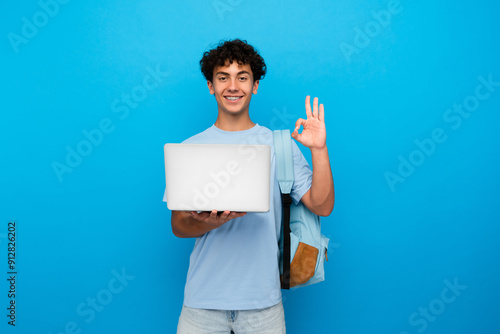 Canvas Print Young teenager high school boy guy holding laptop computer showing okay gesture