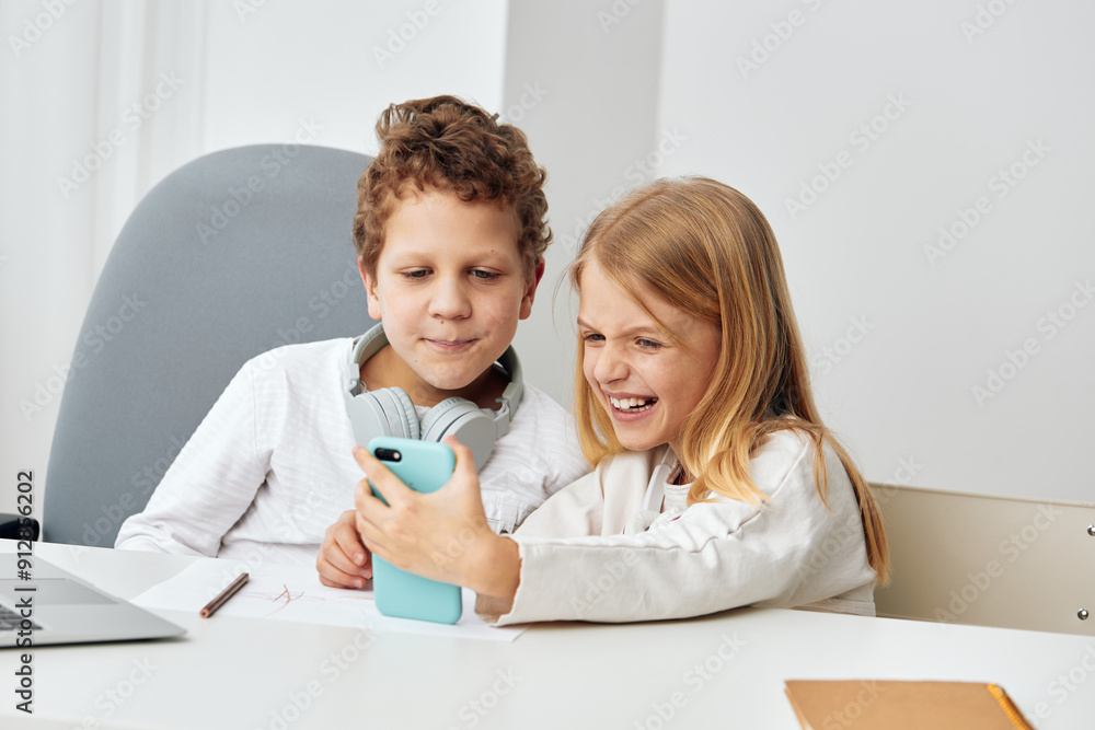 Happy Caucasian siblings studying at home, using technology for online learning The boy and girl, seated at a table in the living room, are wearing headphones while concentrating on their laptops and Happy Caucasian siblings studying at home, using technology for online learning The boy and girl, seated at a table in the living room, are wearing headphones while concentrating on their laptops and