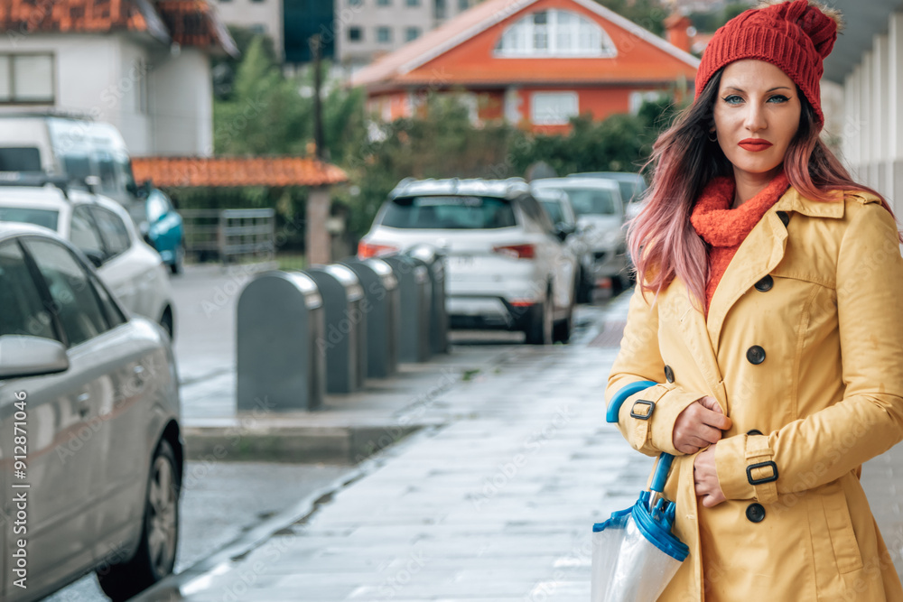 Fototapeta premium Young woman in trench coat and umbrella walking down the street