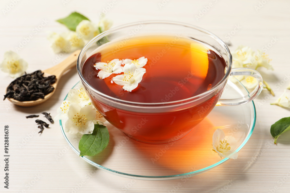 Hot jasmine tea in cup and flowers on white wooden table Hot jasmine tea in cup and flowers on white wooden table