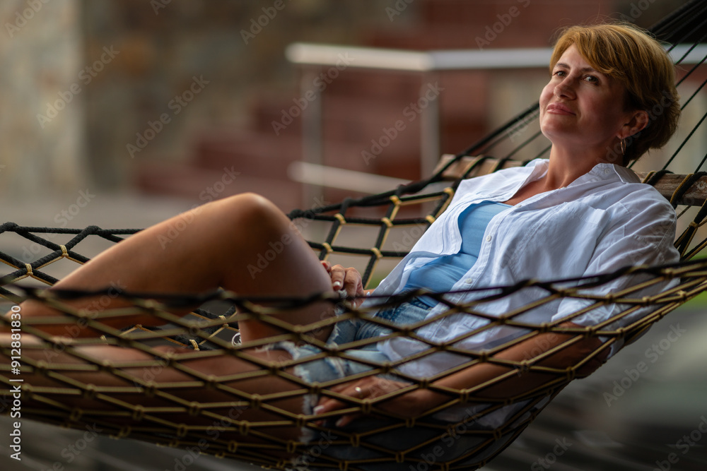 A woman is lying in a hammock near the house.