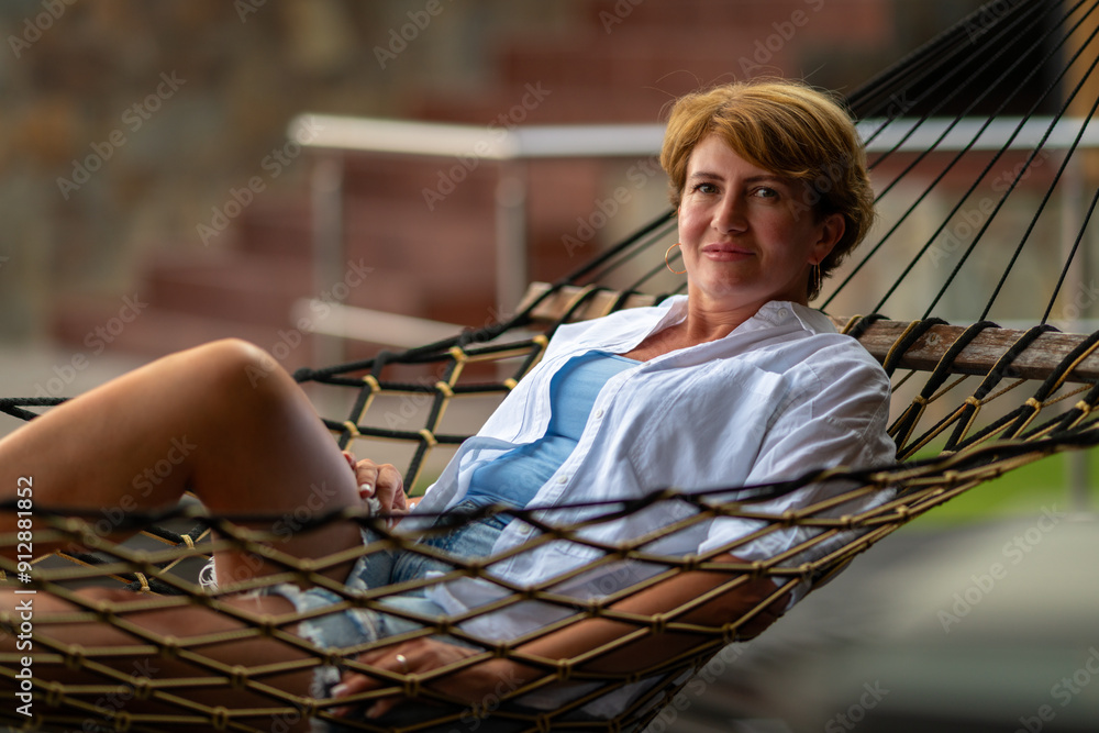 A woman looks at the camera while lying in a hammock.