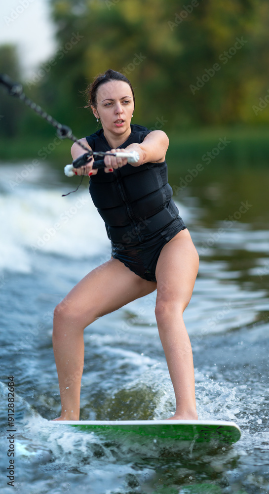Young woman in black swimsuit on wakeboard.