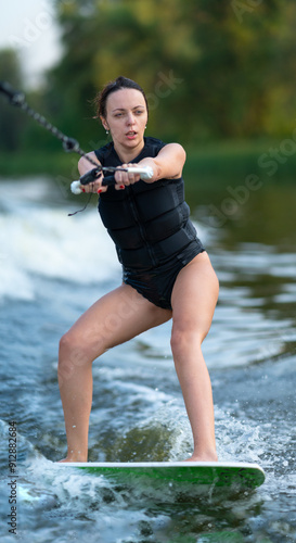 Young woman in black swimsuit on wakeboard.