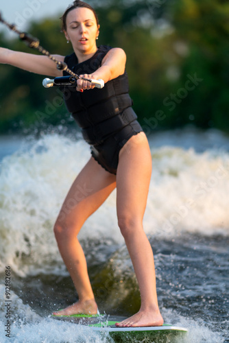 The sportswoman rides a wakeboard with her eyes closed.