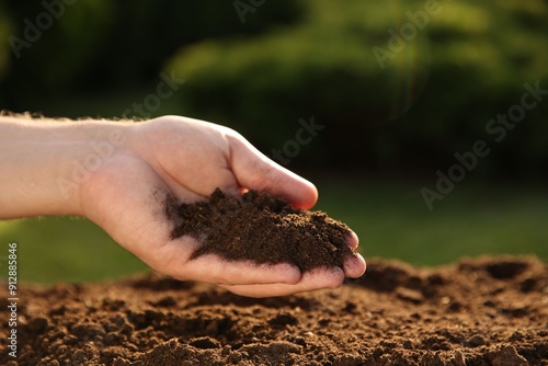 Man holding pile of soil outdoors, closeup. Space for text