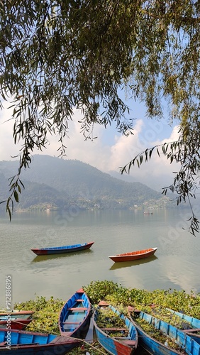 Small fishing boats in the calm Phewa Tal Lake in Pokhara, Nepal photo