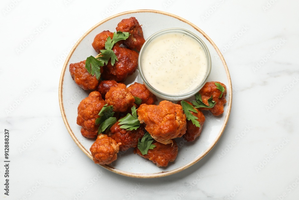 Baked cauliflower buffalo wings with parsley and sauce on white marble table, top view Baked cauliflower buffalo wings with parsley and sauce on white marble table, top view