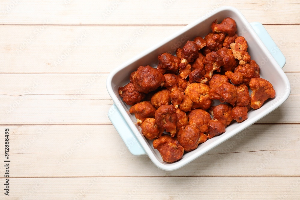 Baked cauliflower buffalo wings in baking dish on wooden table, top view. Space for text Baked cauliflower buffalo wings in baking dish on wooden table, top view. Space for text