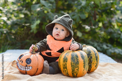 baby dressed in adorable pumpkin costume sits among pumpkins, holding one in each hand. festive spirit of Halloween and charm of childhood in a garden setting.