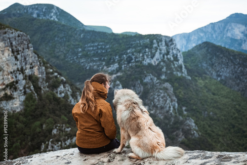 Junge Frau sitzt an der Verdonschlucht mit Blick aufs Tal in Mitten der Natur, genießt die aussicht und kuschelt mit ihrem Eurasier photo