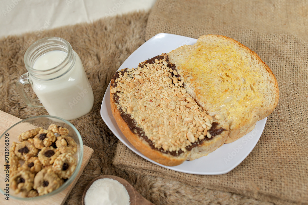Bread with peanut, chocolate and butter spread on a table for breakfast
Bread with peanut, chocolate and butter spread on a table for breakfast