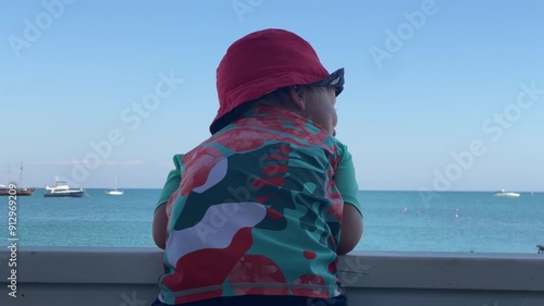 Little boy looking at beach and sea on summer day. Happy child on Tereshkova embankment. Yevpatoria, Crimea, Russia 2024 photo