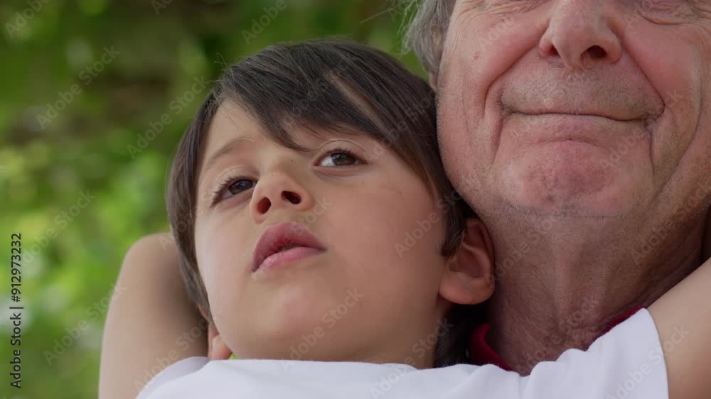 Close-up of grandfather and grandson embracing, both looking thoughtful and content, with a background of green foliage, capturing a tender moment of family love and connection Close-up of grandfather and grandson embracing, both looking thoughtful and content, with a background of green foliage, capturing a tender moment of family love and connection
