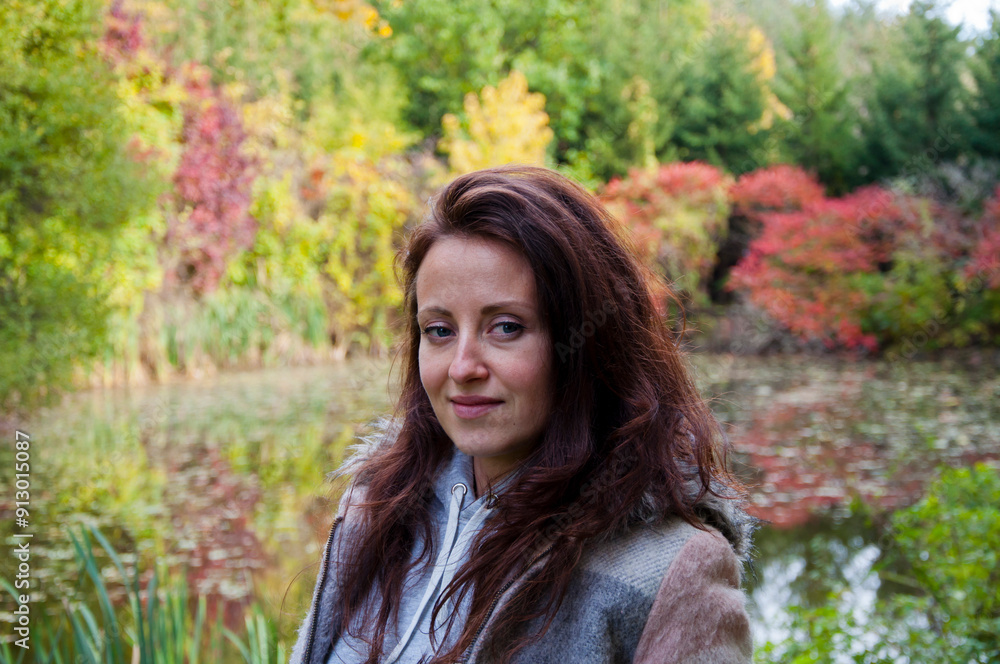 Girl in autumn style at pond. Girl and lake pond. Autumn girl outdoor in park. Central park in fall season. Fall woman in park. Autumn woman outdoor. Woman in fall nature. Change colors Girl in autumn style at pond. Girl and lake pond. Autumn girl outdoor in park. Central park in fall season. Fall woman in park. Autumn woman outdoor. Woman in fall nature. Change colors