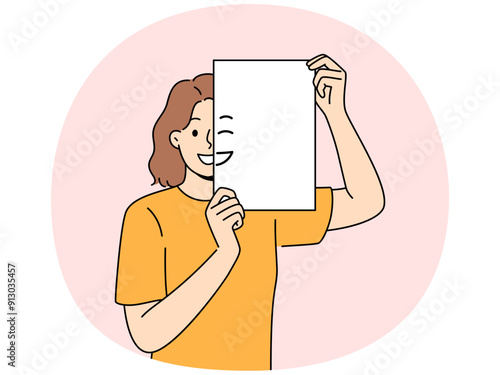 Smiling woman holding piece of paper with emoji in front of face and looking at screen. Positive girl with partially painted smile is sharing good mood and positive emotions with you.