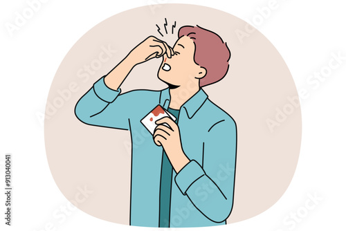 Man pinches bleeding nose and holds bloody handkerchief due to high blood pressure. Young guy with broken nose tries to stop bleeding after fighting and getting punched in face or head