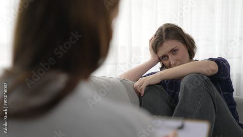 Sad PTSD woman patient in therapy for mental health with psychologist, depression or grief after life failure. Frustrated trauma young woman talking to prim psychologist about emotion in clinic