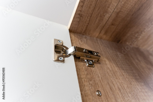 A detailed closeup view of a contemporary cabinet door hinge set within a beautifully crafted wooden interior